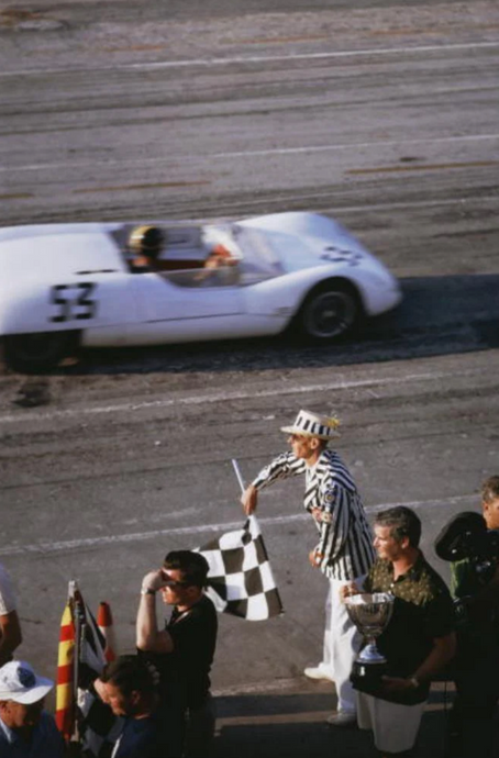 Checkered Flag by Slim Aarons - A vintage photograph of the checkered flag being waved at Bahamas speed week 1963.