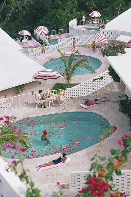 Las Brisas Hotel by Slim Aarons - With striped umbrellas, pale blue water & flowers captured in the shot, this idyllic poolside view by Slim Aarons features a relaxing holiday scene.
