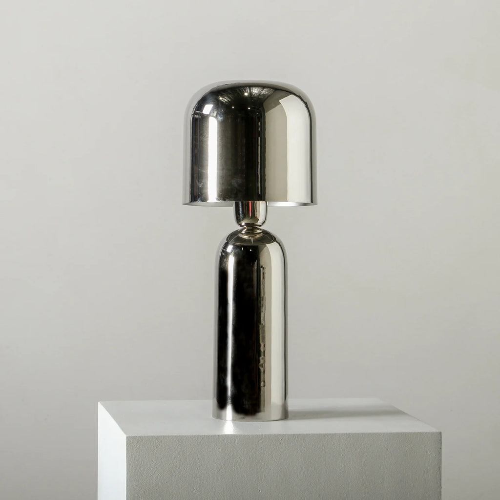 Bolzano Table Lamp Chrome by Indigo Love - Silver table lamp on a white pedestal against a light gray background