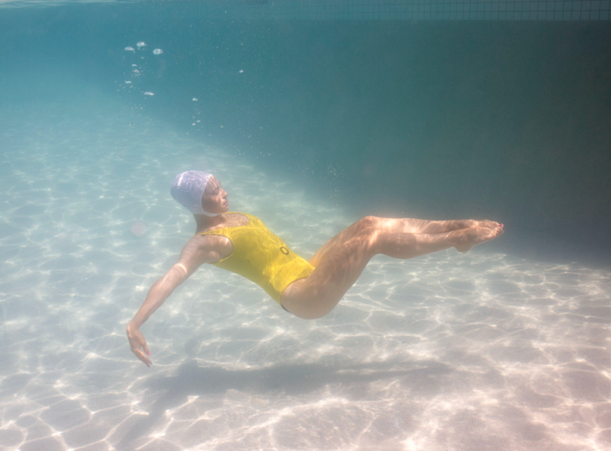 Halcyon Daze 2 by Francesca Owen - Underwater photography of a synchronised swimmer in yellow leotard and white cap posing underwater.