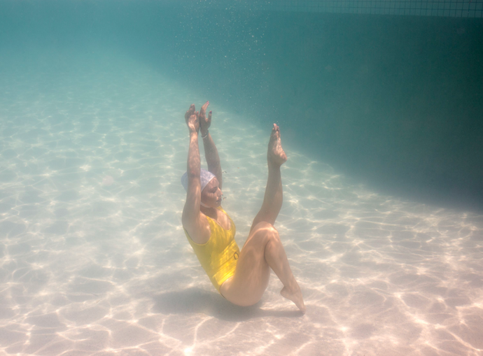  Halcyon Daze 3 by Francesca Owen - Underwater photography of a synchronised swimmer in yellow leotard and white cap posing underwater.