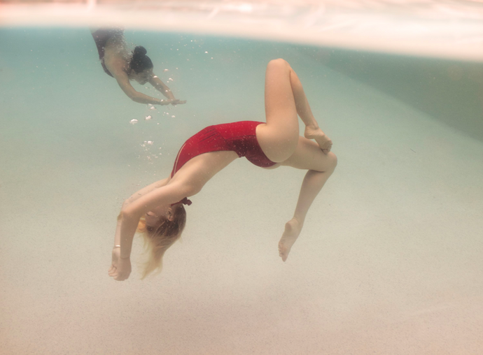 Opposites Attract 1 by Francesca Owen - Underwater photography, swimmers in red bathers posing in water.