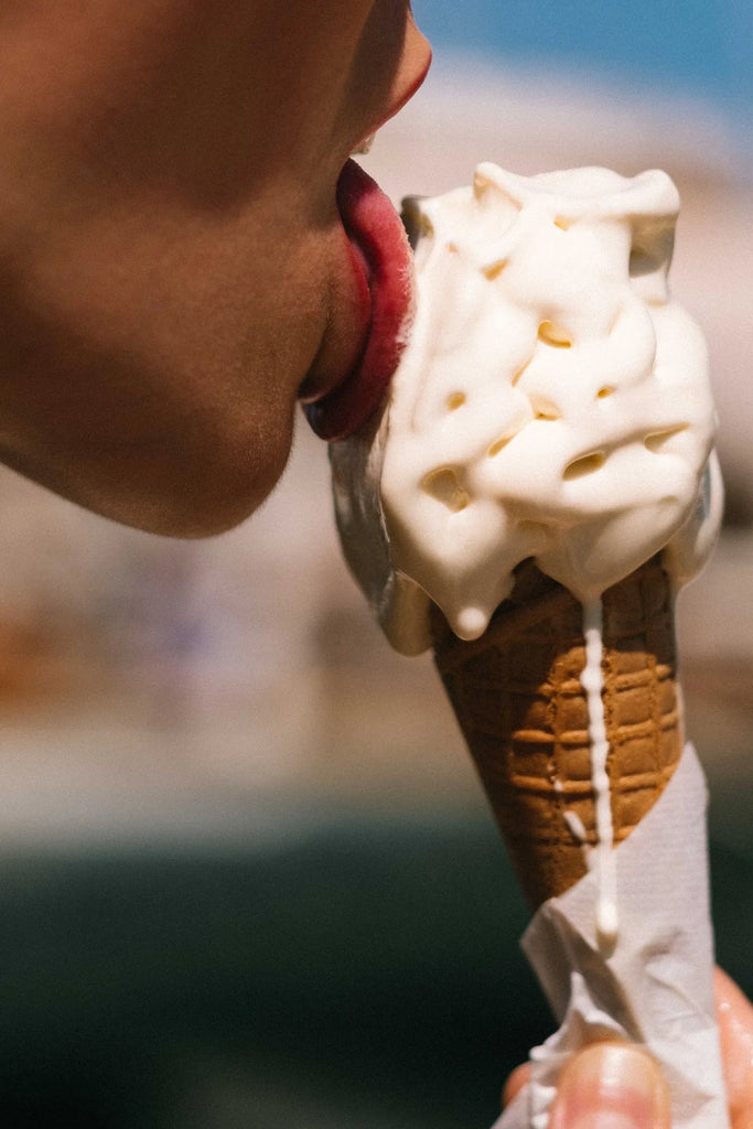 Pause Crème Glacée by Via Tolila - Close-up of a person eating an ice cream cone with a blurred background.