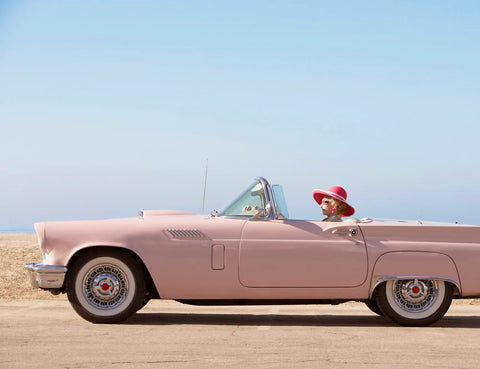 Pink Convertible GettyImages by FINEPRINTCO - Senior woman driving a pink convertible vintage car.