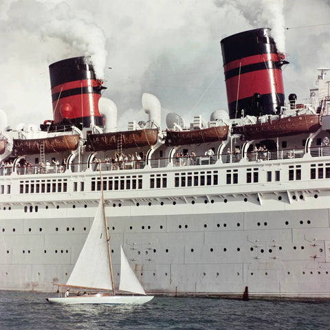 SS Queen of Bermuda by Slim Aarons - Side of large ship with small saiboat