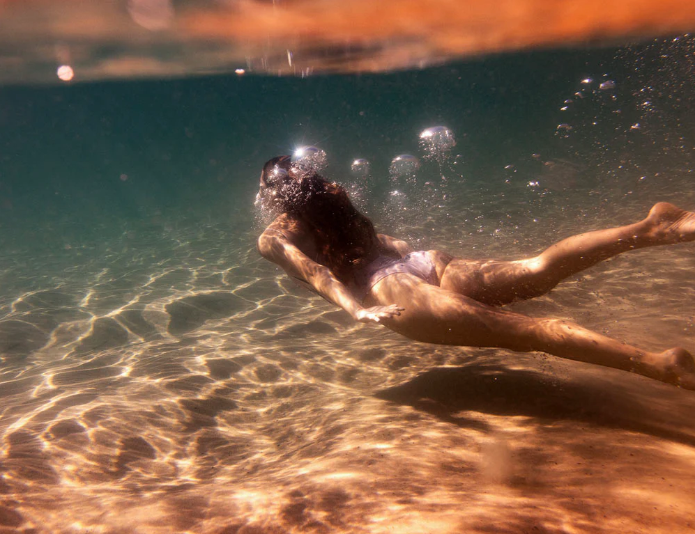 Signature Series - Milos Glow 01 by Francesca Owen - An exquisite underwater scene of a female gliding through the soft warm glow of the waters of Milos, Greece.