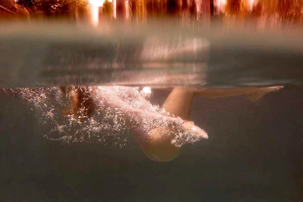 Signature Series - Blush 01 by Francesca Owen - A photographic art print of a woman swimming in a lake, viewed from under the water.