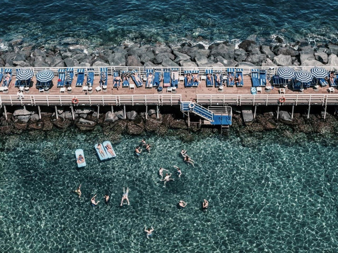 Sorrento Summer Days by Stuart Cantor - A photographic print capturing sunbathers on a pier overlooking views of Sorrento, Italy.