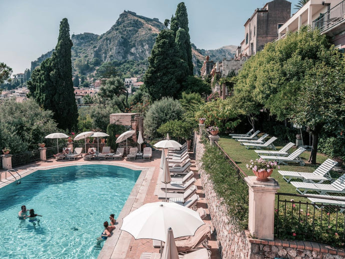 Timeo Time by Stuart Cantor - A photographic print set poolside at the Belmond Grand Hotel in Sicily, with views of the Amalfi Coast in green and blue hues.