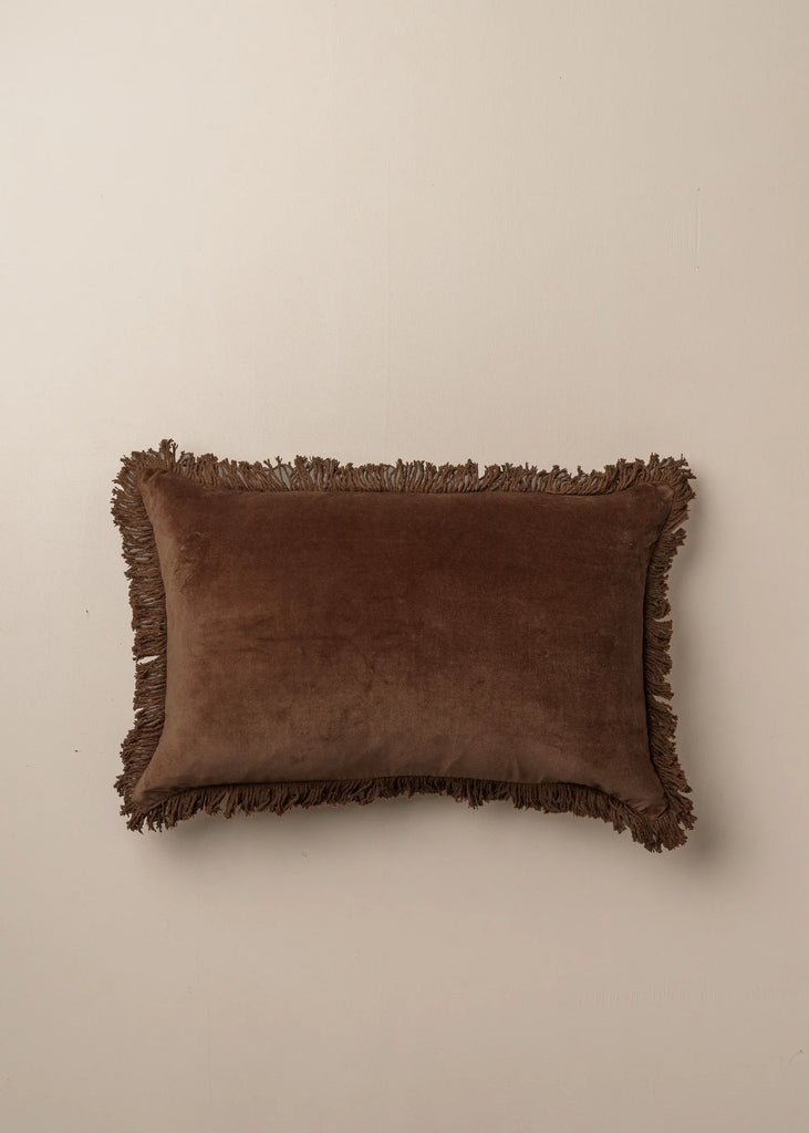 Velvet Fringed Cushion Chocolate by Saarde - Brown pillow with frayed edges on a beige background.