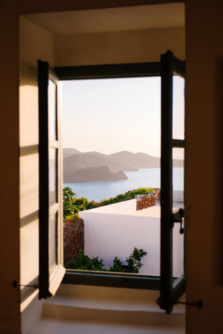Views in Plaka by Via Tolila - Overlooking ocean views out of a window in Milos, Greece.