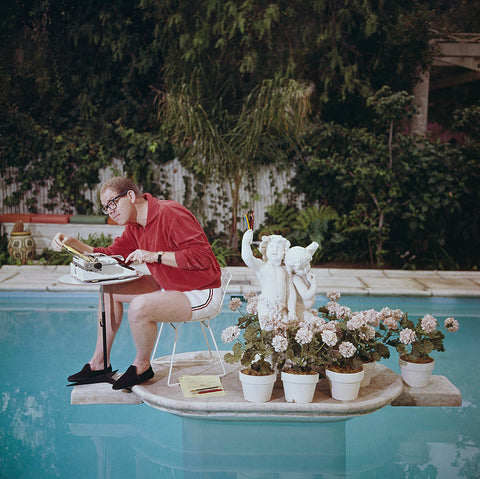Working on Water by Slim Aarons - A photographic print of comedian Stan Freberg working with a typewriter on a platform in his pool.