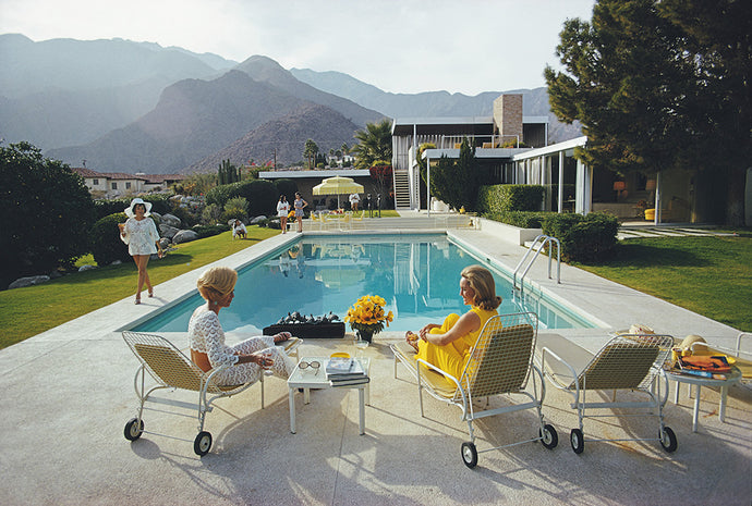 Poolside Gossip by Slim Aarons - A photograph of a Mid Century Modern home in Palm Springs, captured in 1970 by Slim Aarons featuring partygoers by the pool.