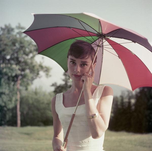 Audrey Hepburn by Getty Images (UK) Ltd - Audrey Hepburn wears a white 50s style sun dress and takes shade on a golf course beneath a colourful umbrella.