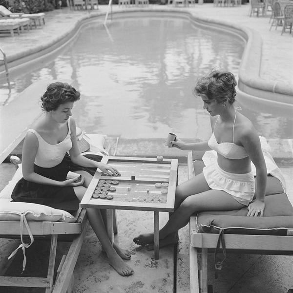 Backgammon By The Pool by Getty Images (UK) Ltd - Vintage black and white photography of two ladies in swimming costumes playing backgammon by the swimming pool, circa 1959