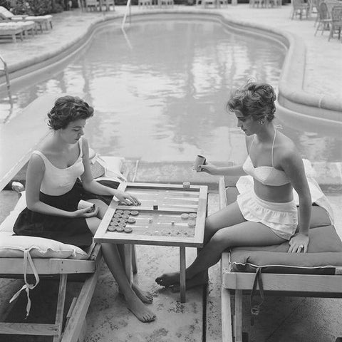 Backgammon By The Pool by Getty Images (UK) Ltd - Vintage black and white photography of two ladies in swimming costumes playing backgammon by the swimming pool, circa 1959