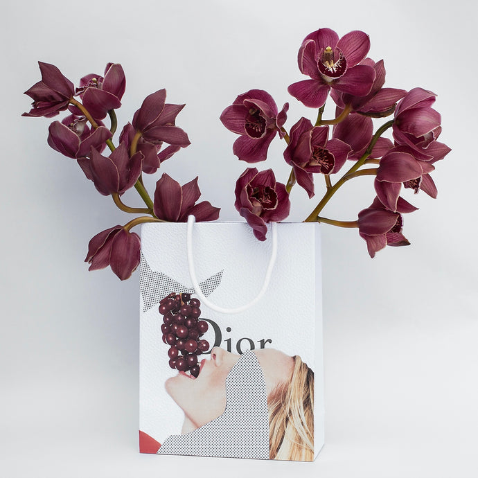  Bagged It (Dior/Grapes) by Dina Broadhurst - A Dior shopping bag filled with burgundy coloured orhids