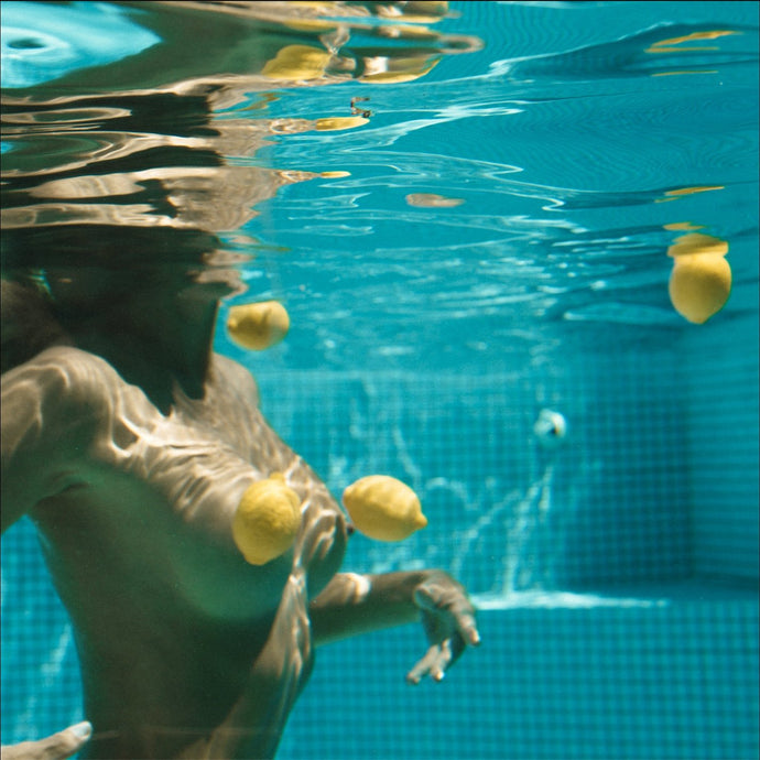 Chance by Dina Broadhurst - Woman wading in the water nude. Bright yellow lemons surround her in the pool.