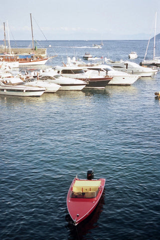 Ferrari by Akila Berjaoui. A film photograph of blue ocean water with a bright red speed boat on the water.