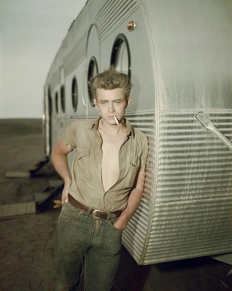 James Dean: A Giant Star by Getty Images (UK) Ltd - Circa 1955: American actor James Dean leaning against a dressing room trailer with his shirt open to the waist while smoking a cigarette on a film set
