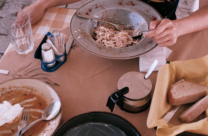 Lunch by Akila Berjaoui. A film photograph of a cafe table with pasta, bread, yellow gingham tablecloth.