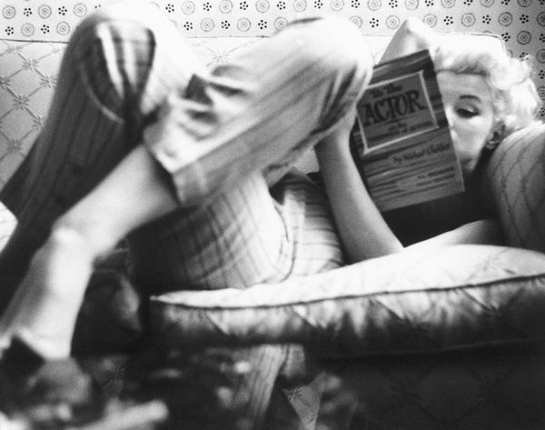 Marilyn Candid Moment by Getty Images (UK) Ltd - Marilyn Monroe candidly reads a book laying on the couch with her legs crossed