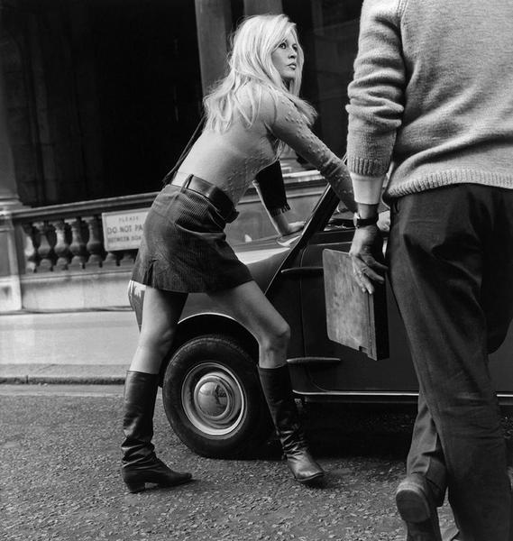 Mini Car Mini Skirt by Getty Images (UK) Ltd - Captured in black and white, Brigitte Bardot leans against a mini car. She is wearing boots, a belted mini-skirt and sweater.