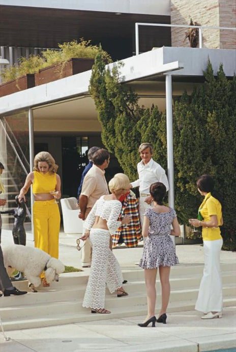 Poolside Chic by Slim Aarons - A group of fashionable partygoers mingle on the steps by the pool, captured in 1970s 