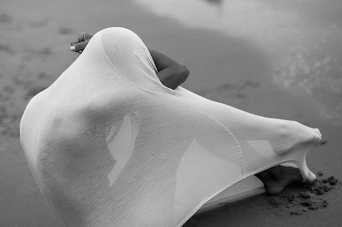Sea Shell by Dina Broadhurst - Photographic artwork of a woman on a beach hiding cocooned in a white t shirt 