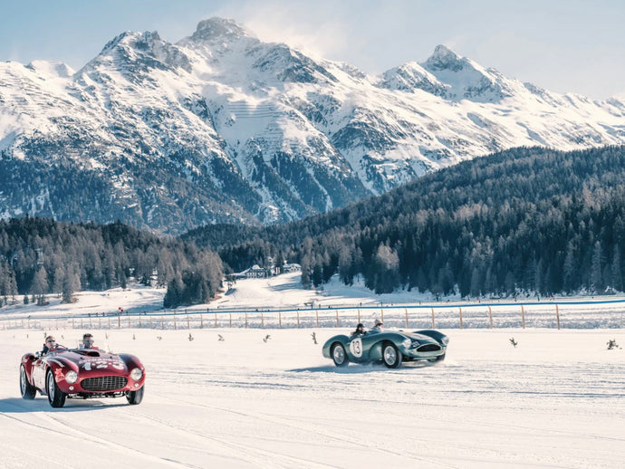 Sun, Speed & Smiles by Stuart Cantor - A snow field in Switzerland with two vintage cars racing, a stunning mountain landscape in the background.