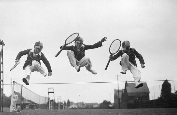 Tennis Leap by Getty Images (UK) Ltd - Playful vintage photograph of three young competitors leaping over the boundary between two tennis courts, wearing 1930s schoolboy uniforms