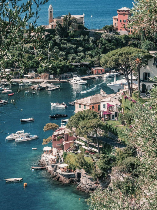 The Jewel by Stuart Cantor - Seaside village of Portofino from above, with speedboats travelling through the deep blue water and terracotta old buildings perch on cliff edges
