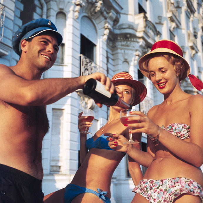 Top Up by Slim Aarons - Partygoers in swimsuits enjoy a glass of wine outside the Carlton Hotel,
