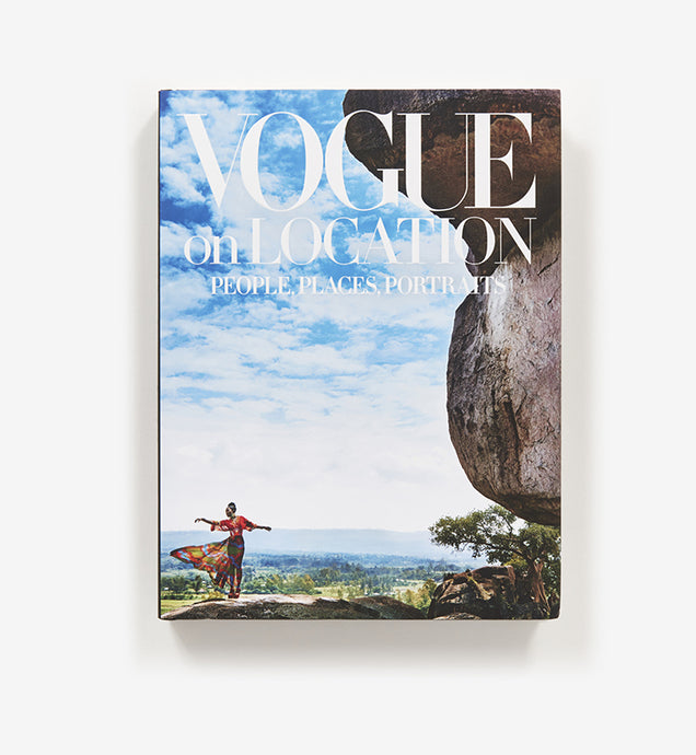 Vogue on Location by Vogue Editors - Blue Skies with clouds with woman in wind swept dress standing next to rock structure